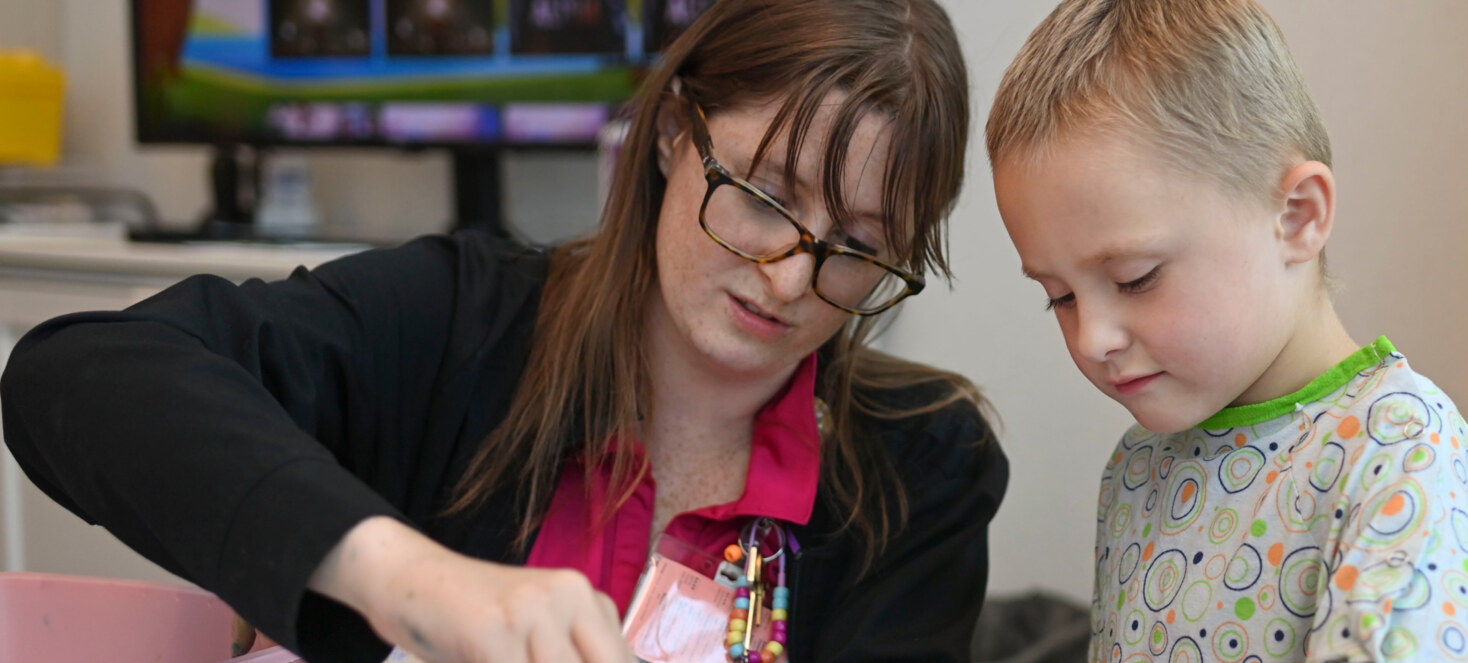 A boy and healthcare worker work together on an exercise