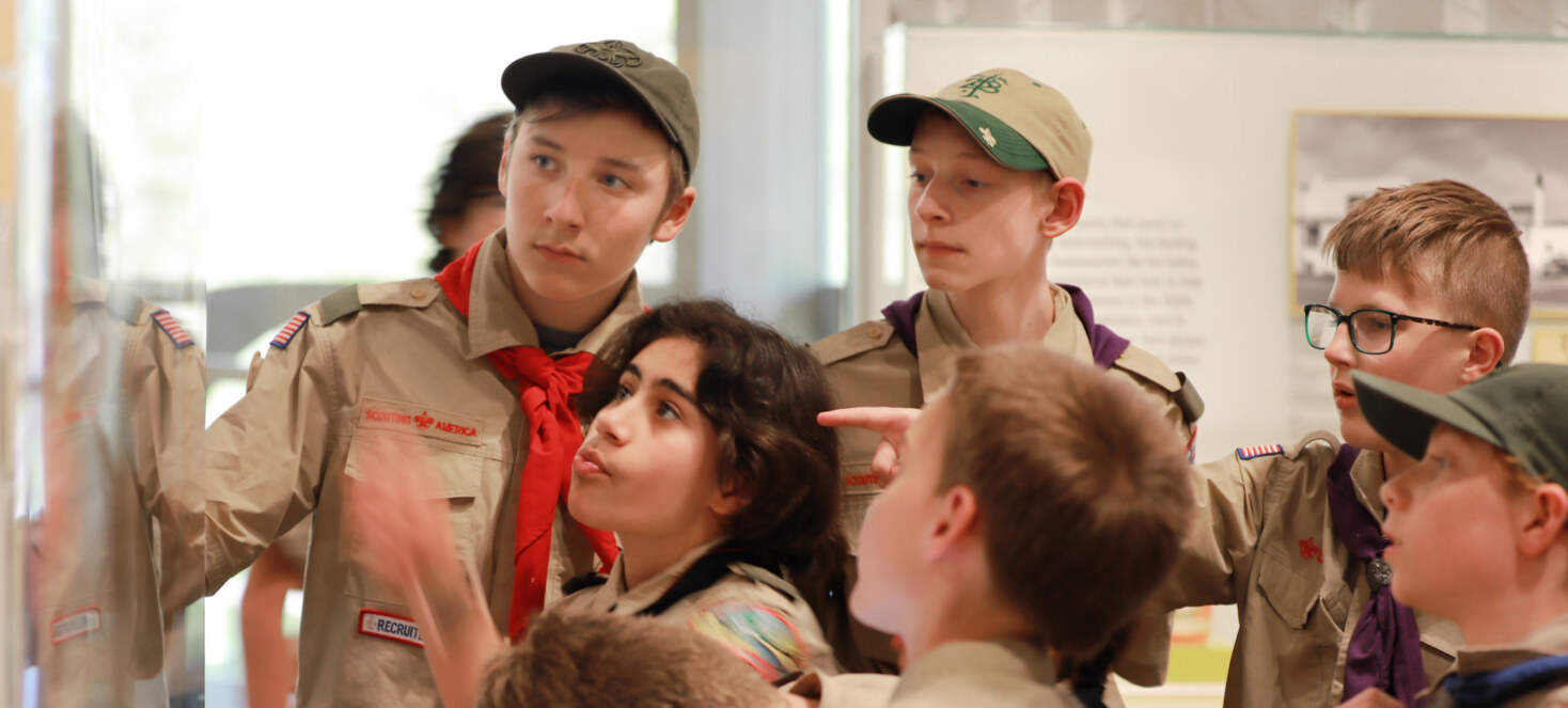 A group of boy scouts reading an exhibit at the museum