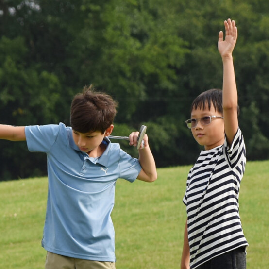 Boy with hand raised on golf course