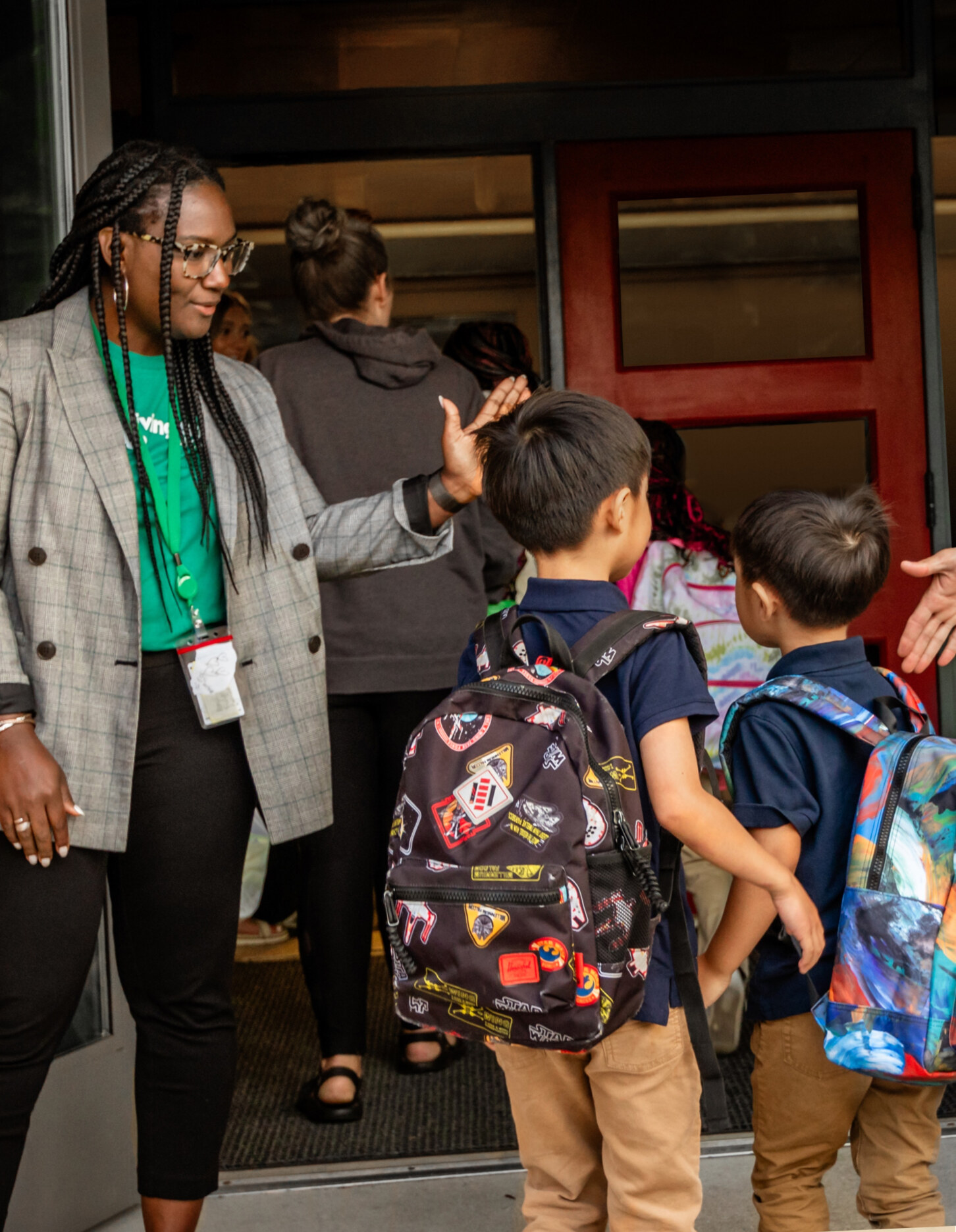 Teacher welcoming children into the door of a facility