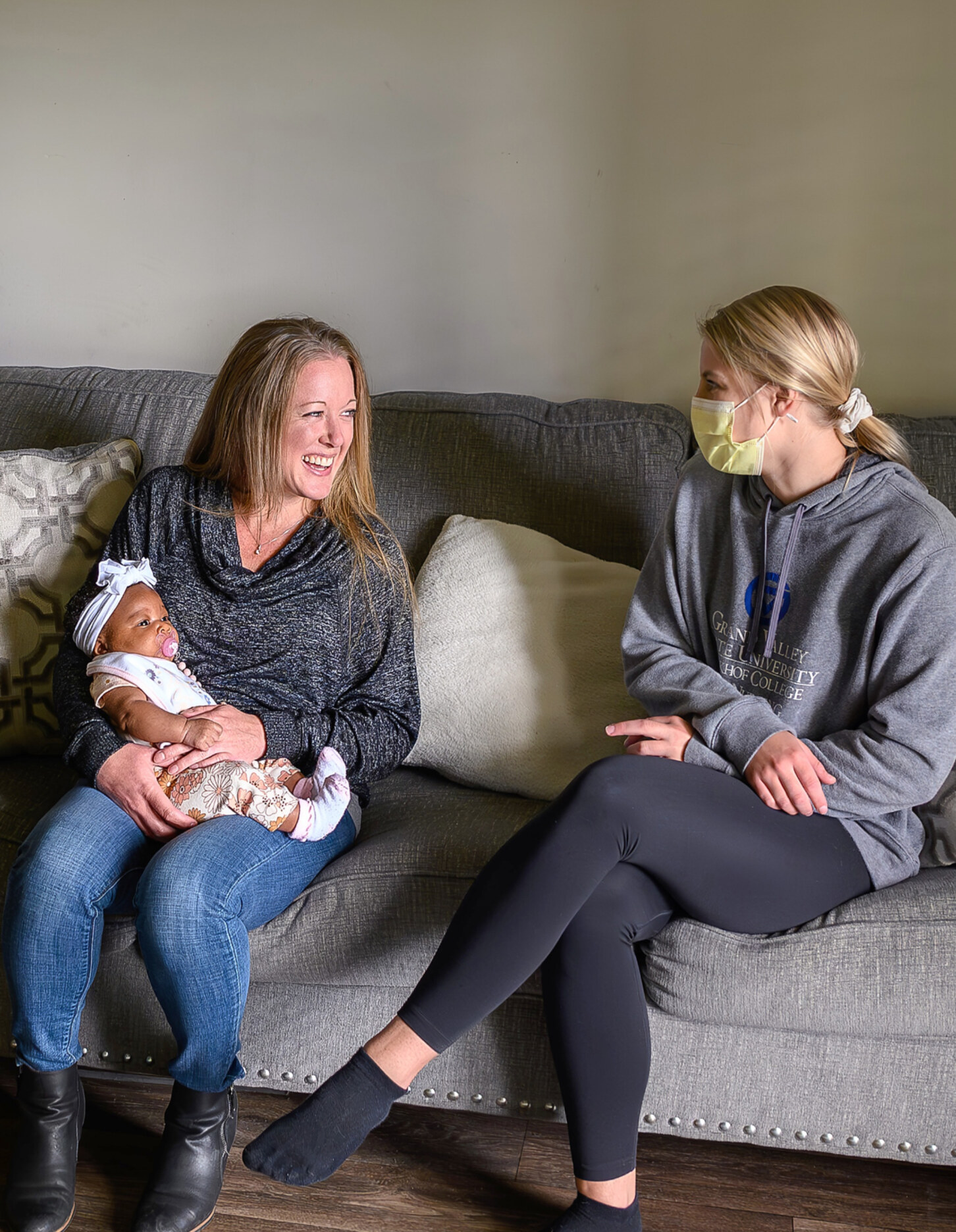 A new mother seated on a couch talking with a support person.
